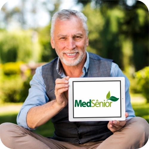 Idoso sorrindo segura tablet com logo MedSênior para análise se o Plano MedSênior vale a pena em São Paulo.